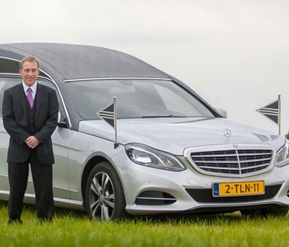 Afbeelding van een begrafenisauto en een begrafenis begeleider